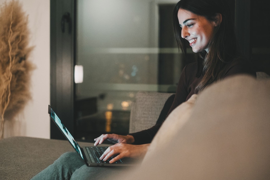 A woman smiles while looking at her laptop